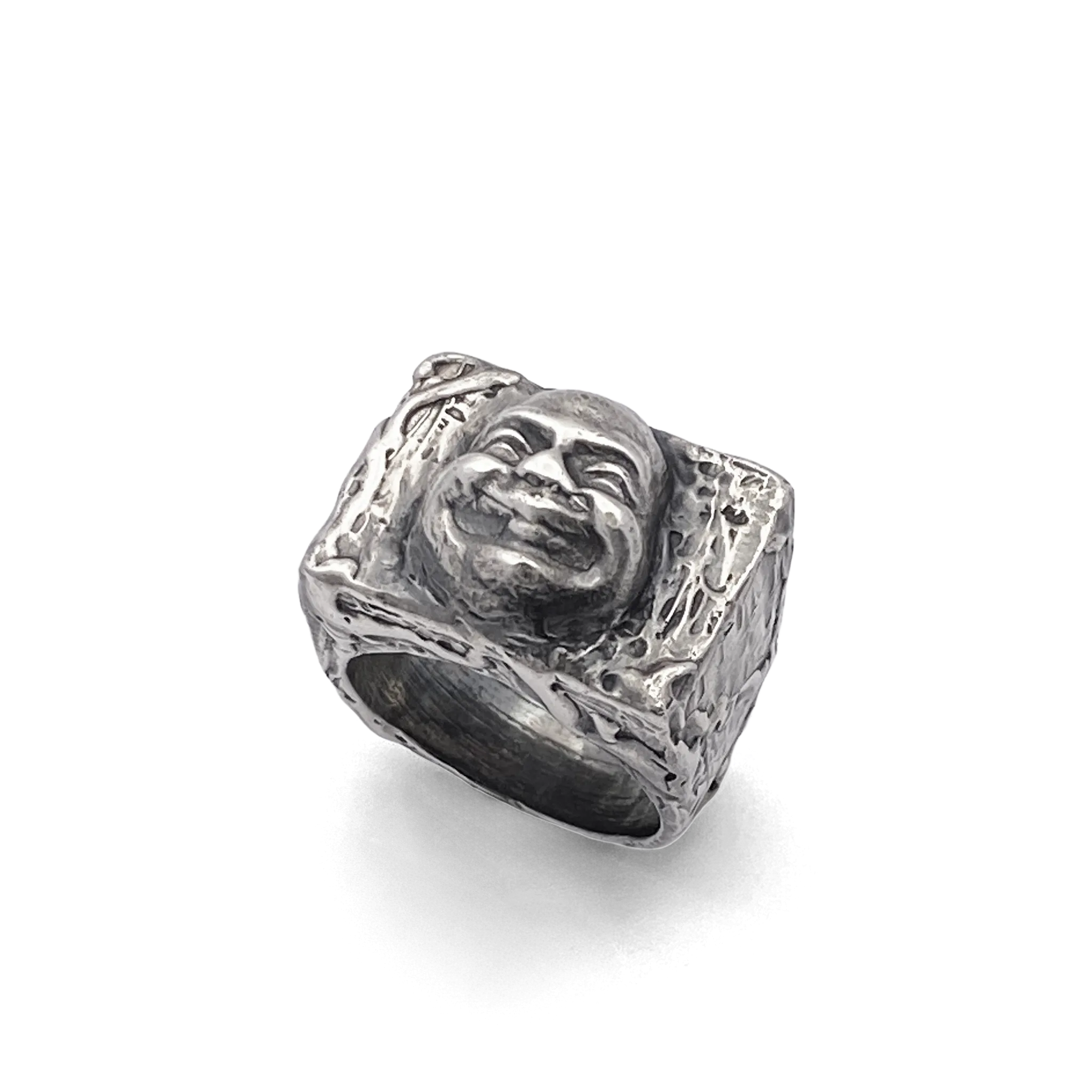 Angled side view of the Buddha Face Ring in oxidised silver on white background