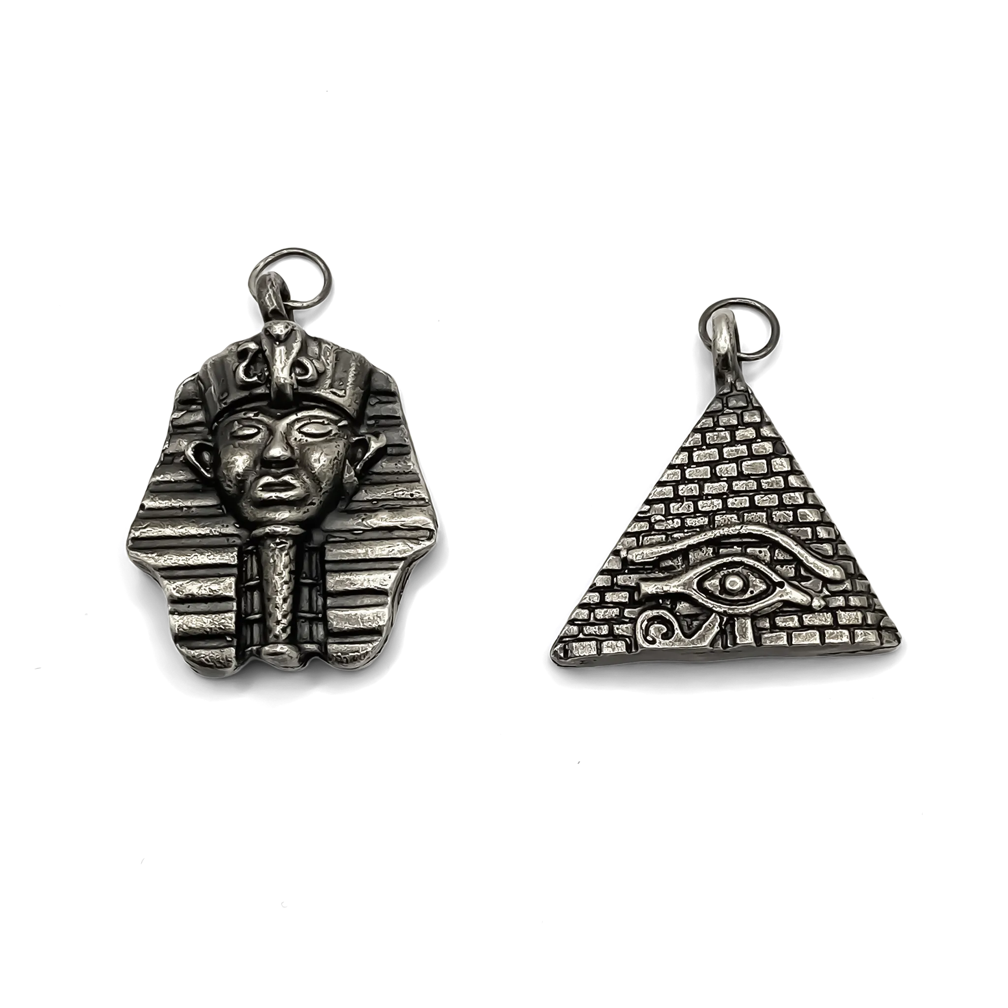 Pharaoh head and pyramid eye pendants in oxidised silver finish, side by side.