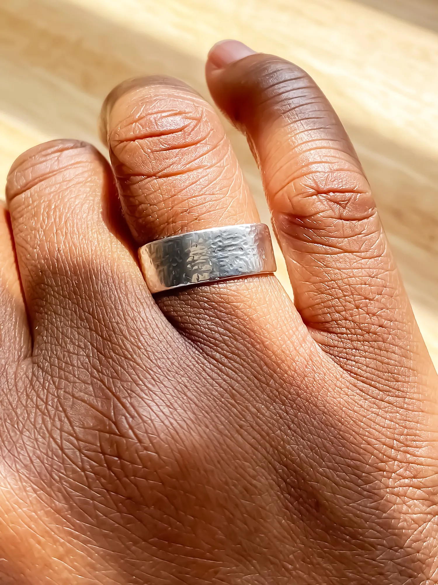 lose-up of hammered silver ring on a hand in natural lighting.