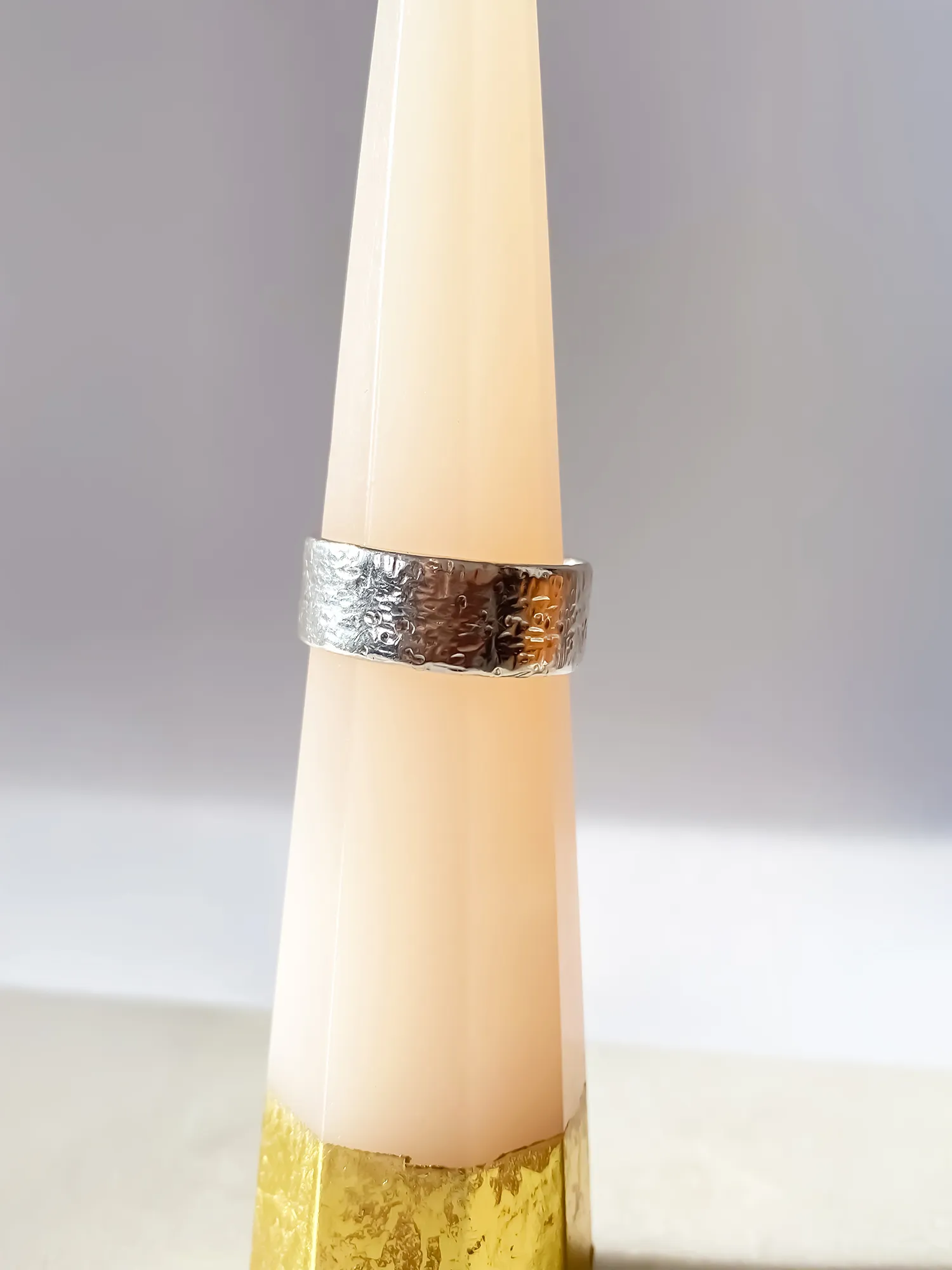 Silver hammered ring displayed upright on a ring cone.