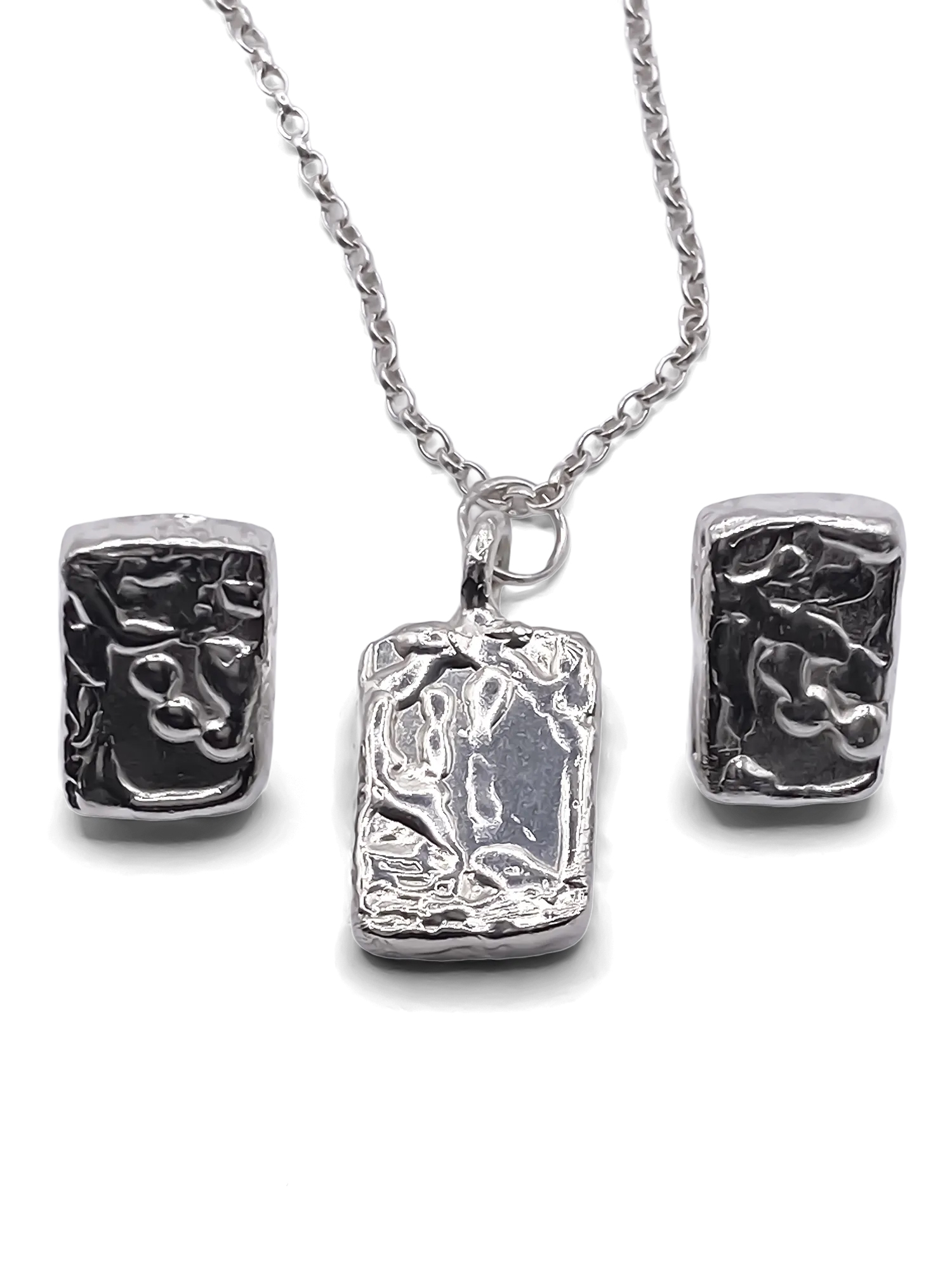 Rectangular sculpted silver earrings and matching pendant on chain, displayed on a white background