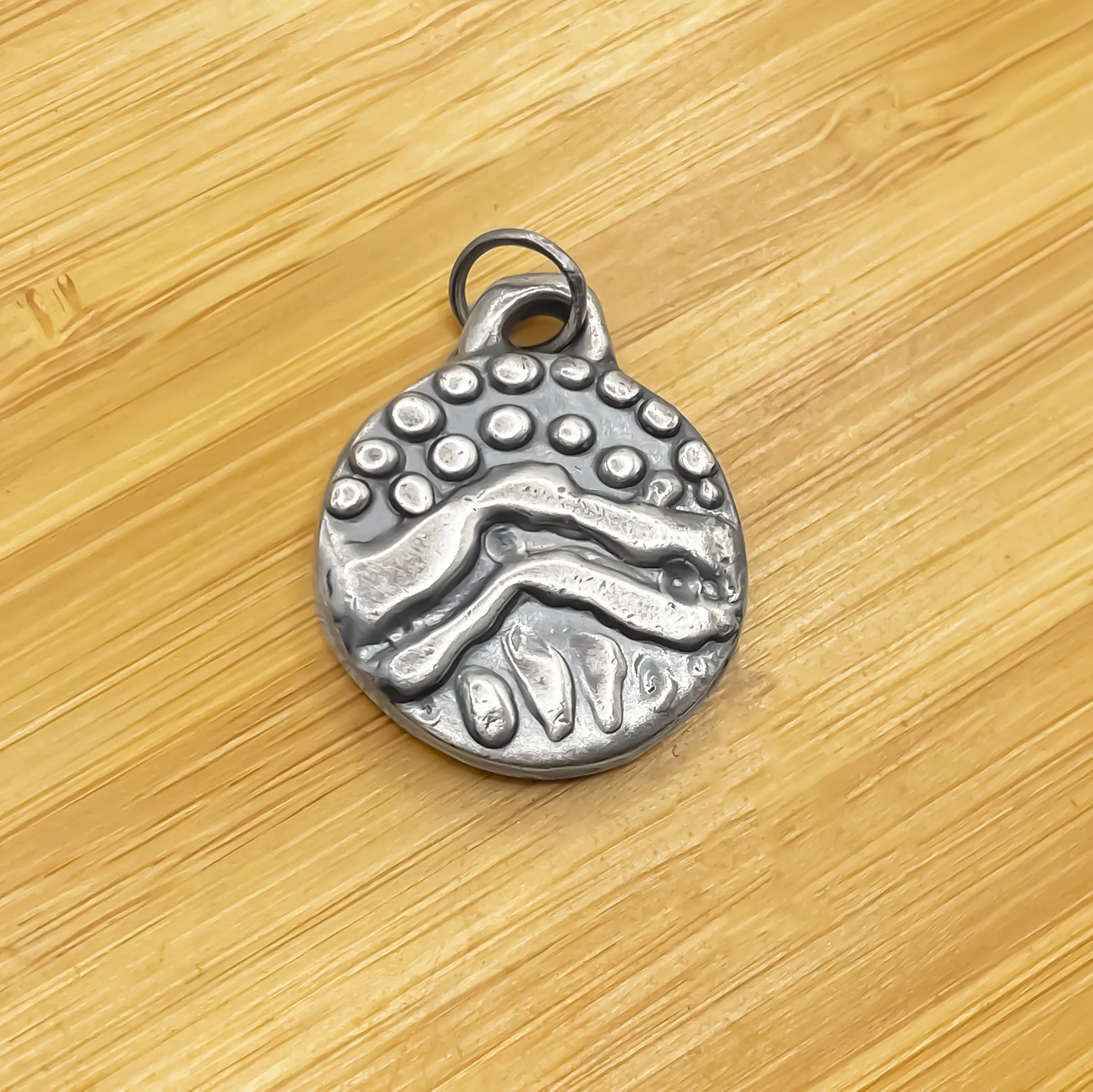 Close-up of Wavy Detail Pendant without chain on wooden background