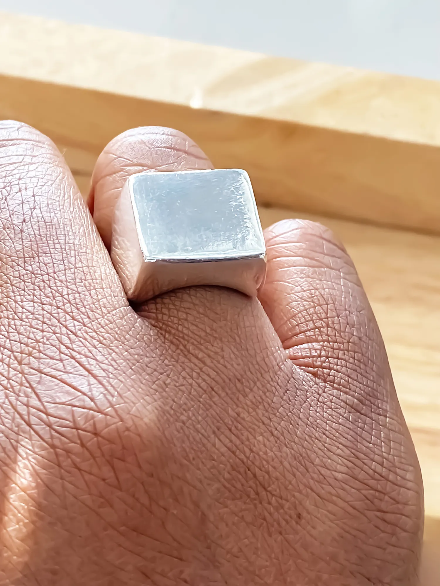 Close-up of silver square signet ring worn on finger from different perspectives