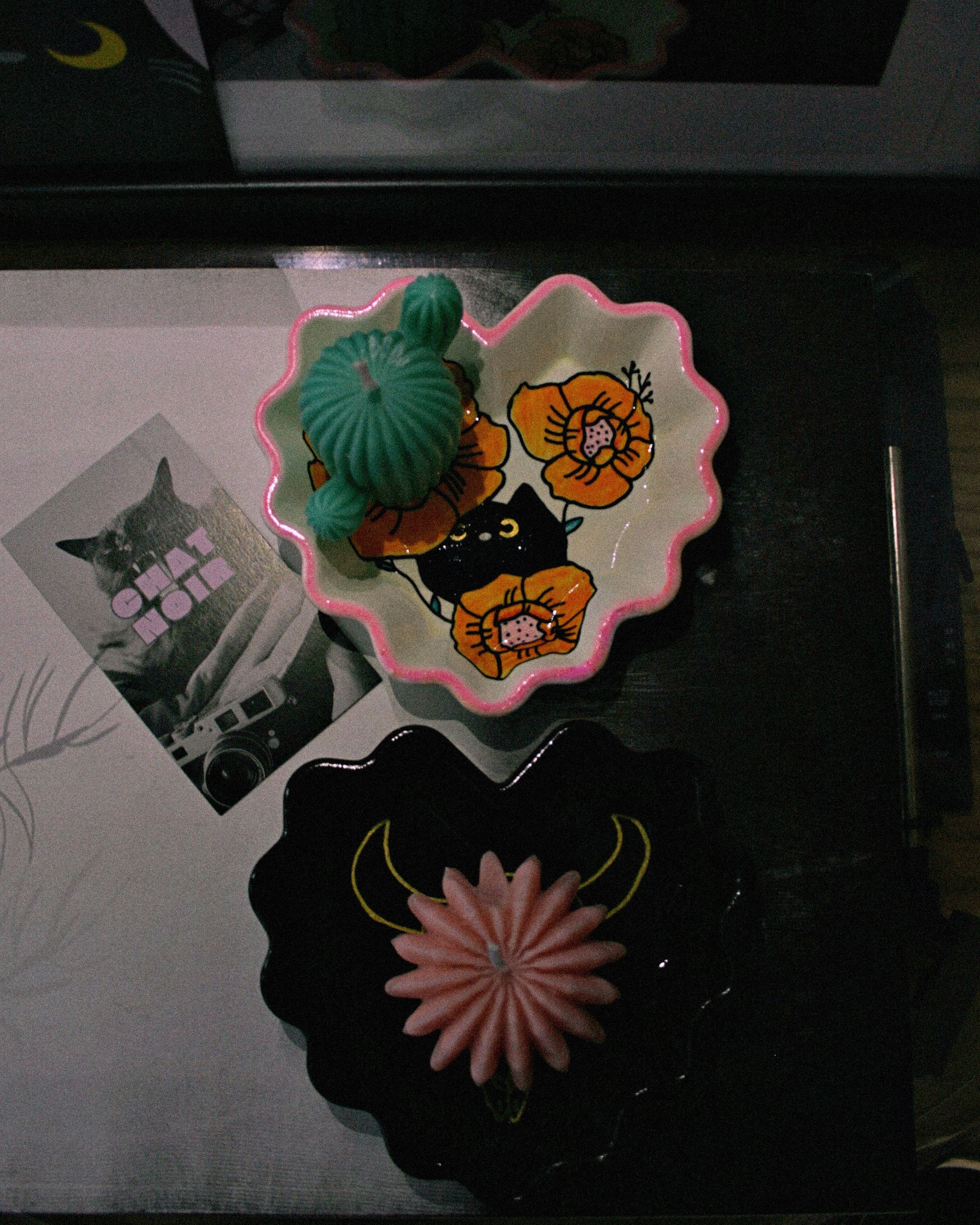 Two heart shaped trays one white with a floral motif and a black cat, one black with a cow skull painted on